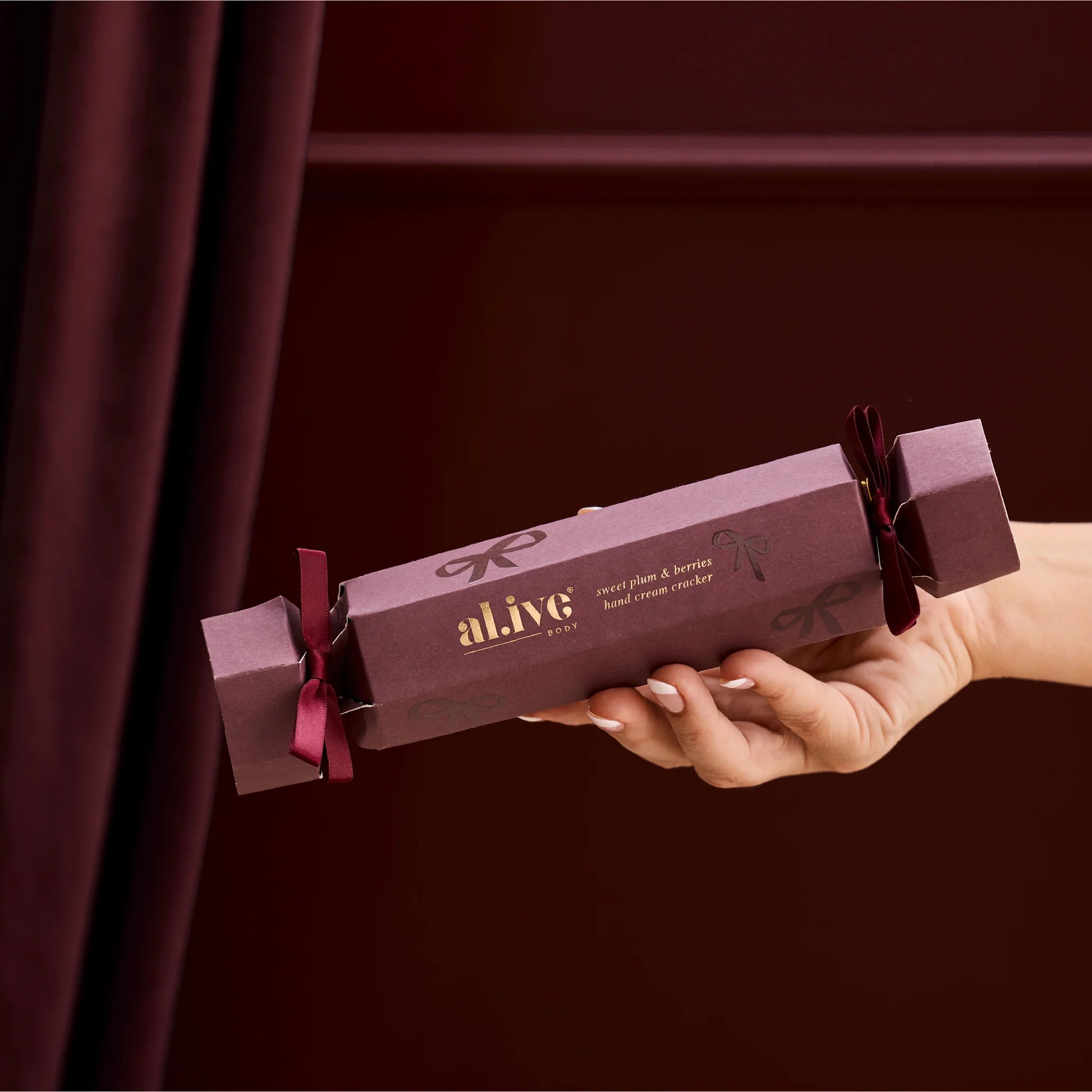 Hand holding a purple 'alive' product packaging against a dark background