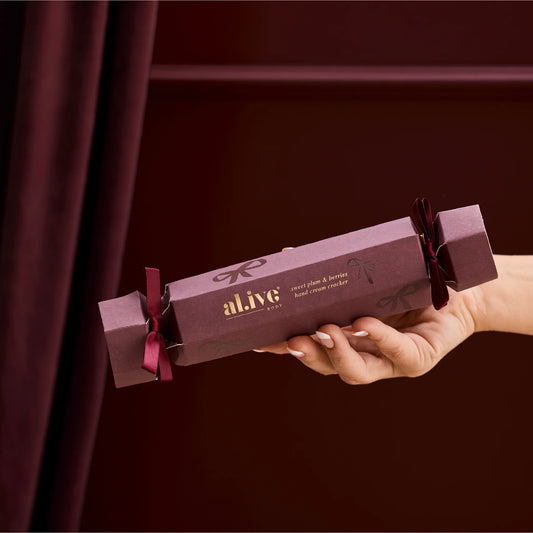 Hand holding a purple 'alive' product packaging against a dark background