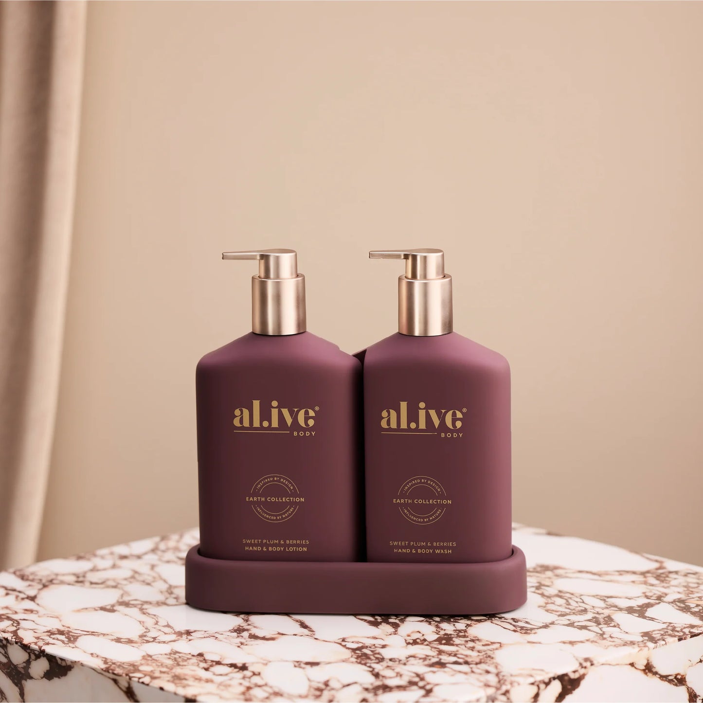 Two purple bottles with gold pumps labeled 'alive' on a marble surface.