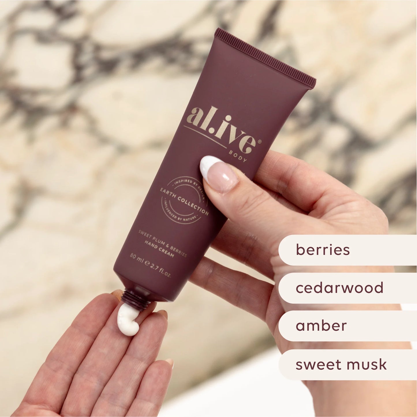 Hand holding a tube of 'alive' body cream with a blurred natural background