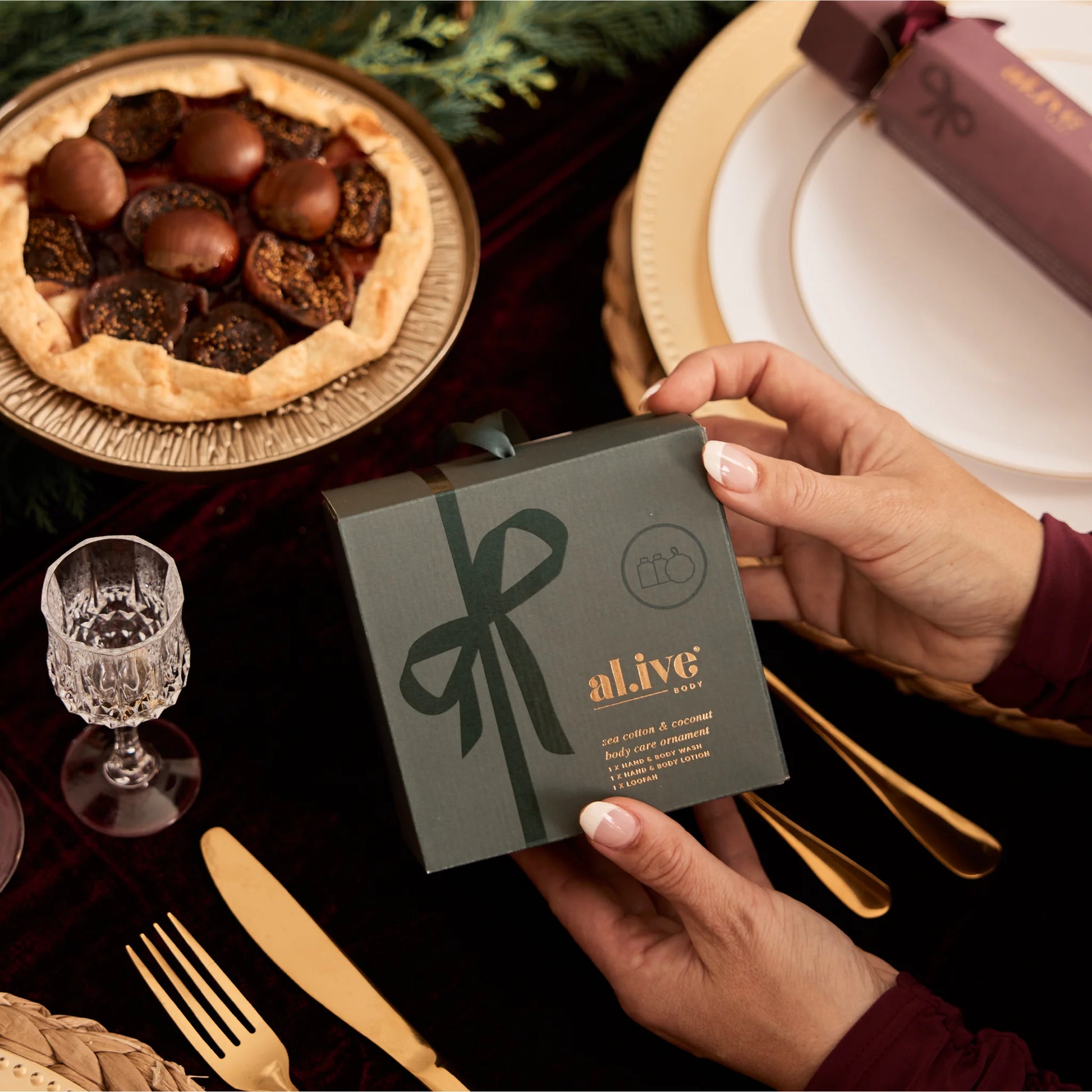 Person holding a 'alive' product packaging with a pie and table setting in the background