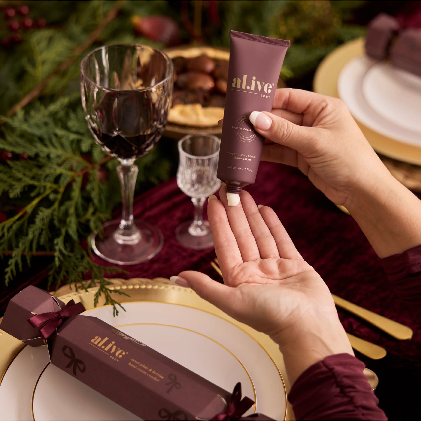 Hand holding a tube of 'al.i.v.e' product with a festive table setting in the background