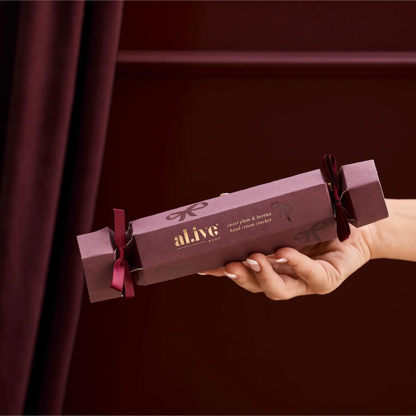 Hand holding a purple 'alive' product packaging against a dark background
