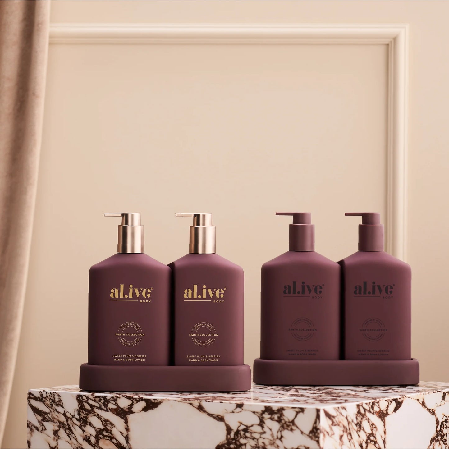 Four purple bottles labeled 'alive' on a marble surface with a beige wall background