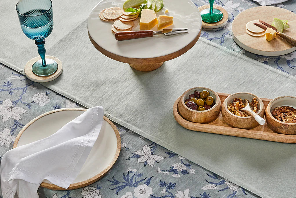 Table setting with a floral tablecloth, plates, and small bowls of food.