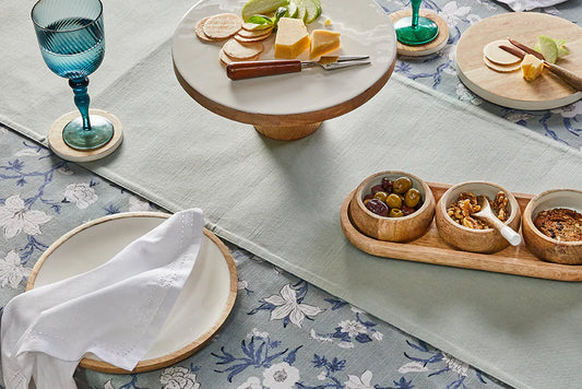Table setting with a floral tablecloth, plates, and small bowls of food.