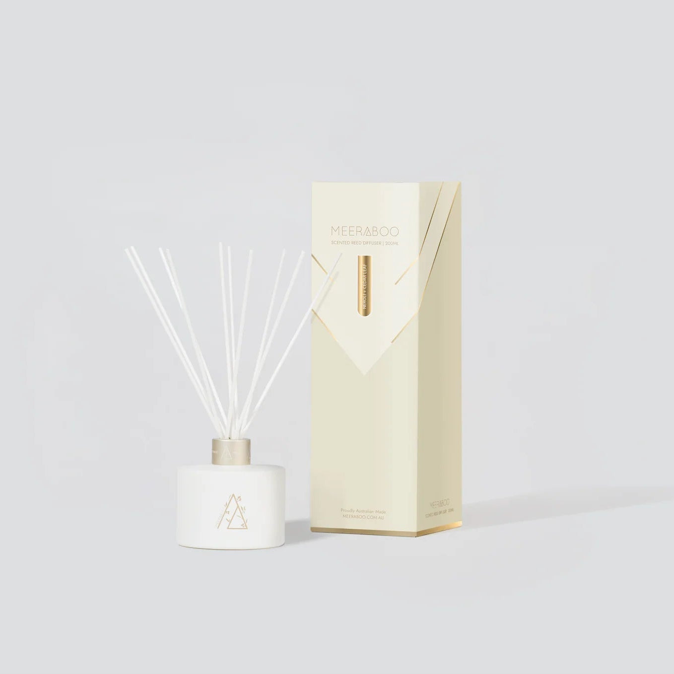 Diffuser bottle with reeds and packaging on a light gray background
