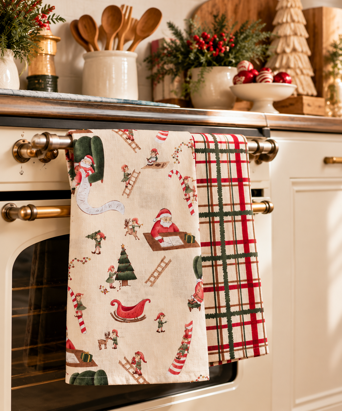 J.Elliot Home Santa's Workshop Christmas cotton tea towels displayed on a kitchen oven with festive Christmas decorations.