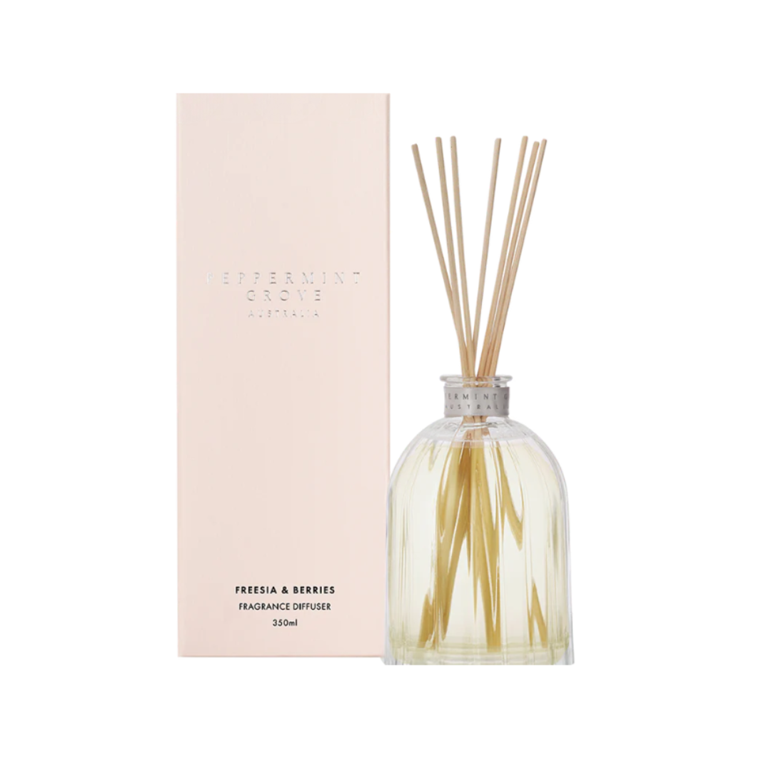 Fragrance diffuser with reeds and pink packaging on a white background
