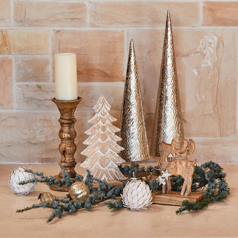 Decorative Christmas scene with gold trees, candle, and ornaments on a stone surface.