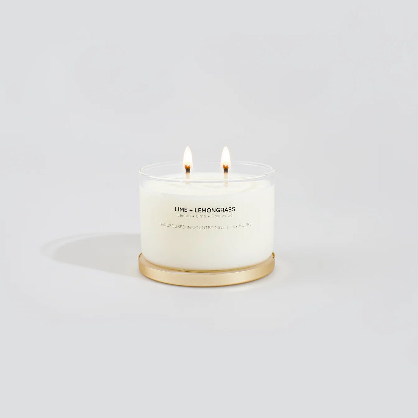 White candle with gold base on a light gray background