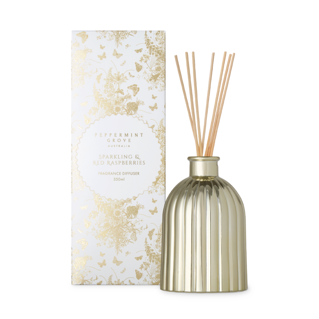 A reed diffuser bottle with natural wood reeds and a matching decorative box, both in white and gold tones, on a plain white background.