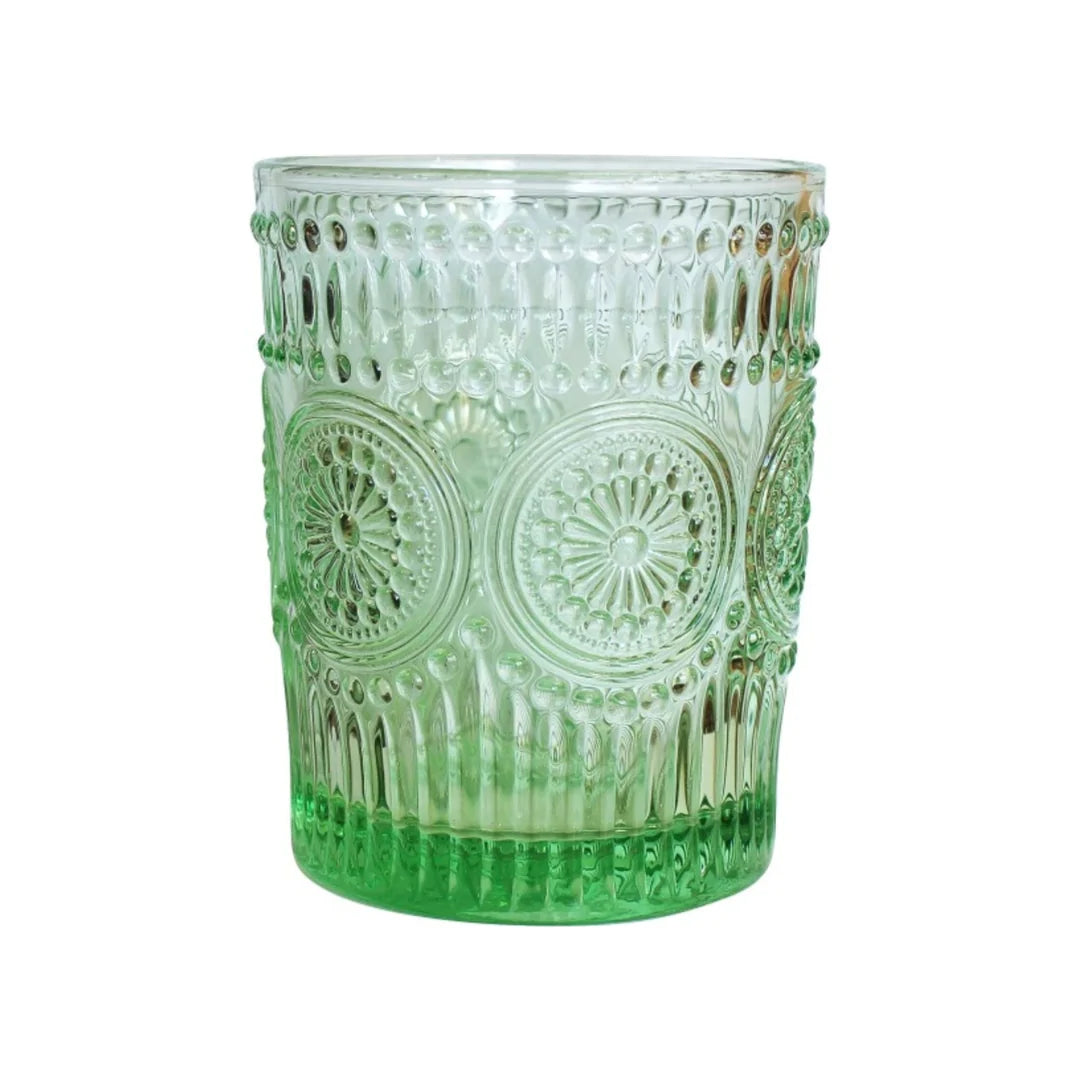 A clear glass tumbler with a green gradient and embossed circular medallion patterns, shown on a plain white background.